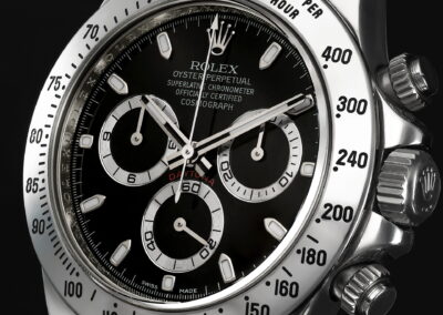 Macro commercial product photography of a Rolex Cosmograph Daytona watch dial, showcasing intricate steel brushed bezel details and crisp black dial, professional watch photographer studio in Hong Kong.